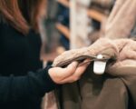 Close-up of a woman examining a coat in a clothing store, focused on texture and design.